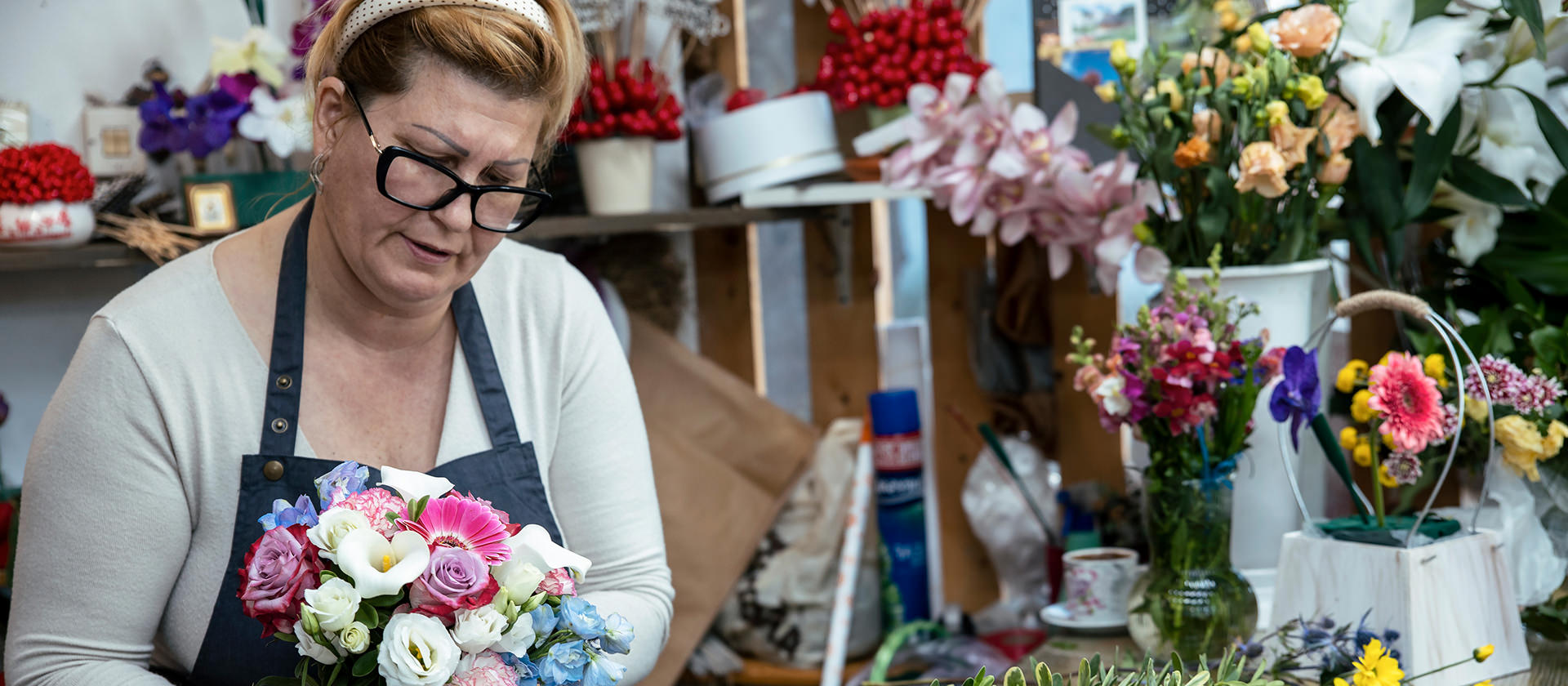 Illustratives Foto: Eine Floristin bei der Arbeit bindet einen Blumenstrauß